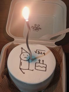 a birthday cake with a lit candle on top in a box for someone to eat