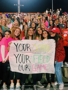 a group of girls holding up a sign in front of an audience at a game