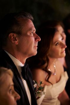 a man in a tuxedo sitting next to a woman wearing a white dress