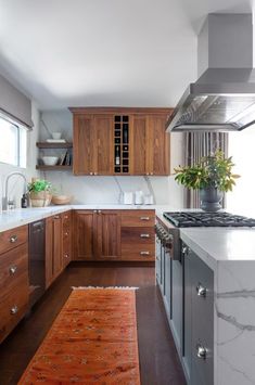 a kitchen with wooden cabinets and white counter tops, an orange rug on the floor