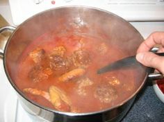 a person stirring food in a pot on the stove