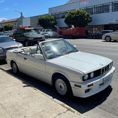 a white car parked on the side of a road next to a parking lot with other cars