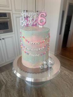 a birthday cake with pink and blue frosting is on a table in the kitchen