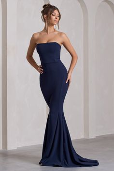 a woman in a strapless blue gown with her hands on her hips, posing for the camera