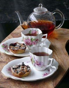 three teacups and two plates with pastries on them