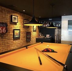 a pool table in the middle of a room with lights on and pictures above it