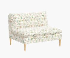 an upholstered couch with wooden legs and floral print on the back, against a white background