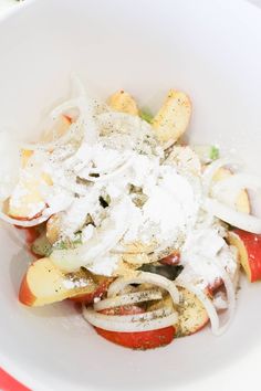 a white bowl filled with lots of food on top of a red and white table