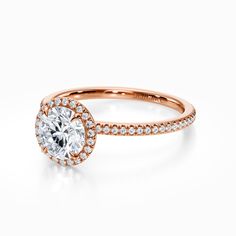 a rose gold engagement ring with an oval diamond center and pave set diamonds around the band