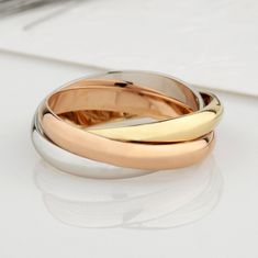 two gold wedding rings sitting on top of a white table next to a laptop computer