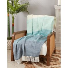 a chair with a blanket on top of it in front of a potted plant