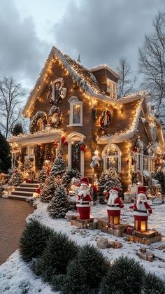 a house covered in christmas lights with santas on the front porch and trees around it