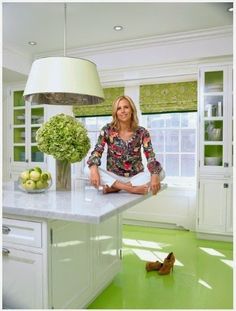 a woman sitting on top of a kitchen counter in front of a lamp and flowers