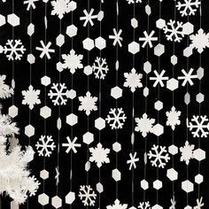 snowflakes are hanging from strings on a black background with white snow flakes