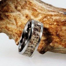 two wedding bands with antler wood inlays on each side, sitting next to a rock