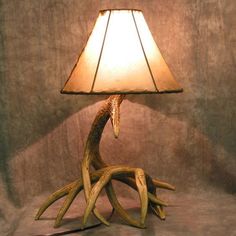 a lamp made out of antlers with a light shade on the top and bottom