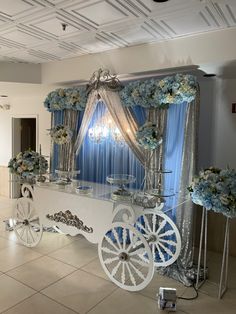 a white horse drawn carriage with blue flowers on the front and side, sitting in an empty room