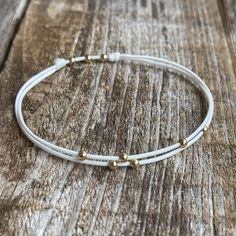 "Our \"Amelia\" bracelet/anklet is the perfect accessory for those who love minimalism and simplicity. The delicate string and small shining gold beads make for a subtle yet stylish addition to any outfit. Named after the charming Amelia Island off the coast of Florida, this anklet captures the island's relaxed and understated beauty. Whether you're strolling along the beach or exploring the city, our Amelia anklet is the perfect way to add a touch of effortless style to your everyday look. - Th Delicate White Adjustable Anklets, Dainty Adjustable Hypoallergenic Anklets, Hypoallergenic Adjustable Dainty Anklets, Dainty Hypoallergenic Adjustable Anklets, Adjustable Gold Minimalist Anklet, Adjustable Minimalist Gold Anklet, Minimalist Adjustable Hypoallergenic Anklet, Adjustable Hypoallergenic Minimalist Anklet, Beaded Anklet