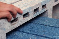 a hand is holding the edge of a bench made out of concrete blocks and bricks