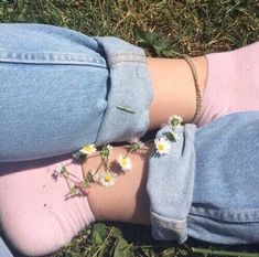 a pair of jeans with flowers attached to the side of their legs, sitting in grass