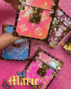 a person is holding up some pink and blue magnets with gold foil on them