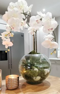 a vase filled with white flowers sitting on top of a table next to a candle