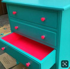 a green dresser with red knobs and drawers on the bottom drawer is painted teal