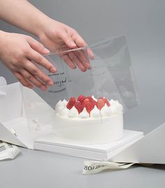 a person cutting into a cake with strawberries on top