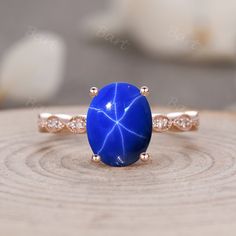 a blue stone ring sitting on top of a piece of wood with diamonds around it