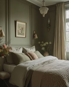 a bedroom with green walls and white bedding in front of a window filled with flowers