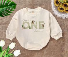 a white sweatshirt with the words one and two birds on it next to some flowers