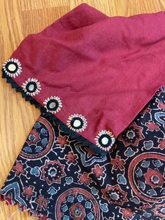 A beautiful hand block printed (Ajrakh) pure cotton blouse in sizes 40 and 42 with hand embroidered mirror (authentic mirror- not mica) with elbow sleeves. The body has the ajrakh print in a black base while the sleeves are in contrast - dark maroon. Blouse is padded with hook in the back. Front and back both are U shaped neckline. Extra margin available to increase up to one size. You may reach out to us for alterations. Size change is a $5 extra charge. Note: We try to stay as accurate to the Unstitched Cotton Blouse Piece With Printed Motifs, Bohemian Unstitched Cotton Blouse Piece, Festive Cotton Kalamkari Blouse Piece, Traditional Cotton Blouse Piece With Kalamkari Print, Festive Cotton Bandhani Print Blouse Piece, Unstitched Bohemian Cotton Blouse Piece, Cotton Bandhani Print Blouse For Navratri, Cotton Blouse Piece With Bandhani Print For Navratri, Festive Cotton Bandhani Blouse Piece