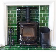 a wood stove in a green tiled room