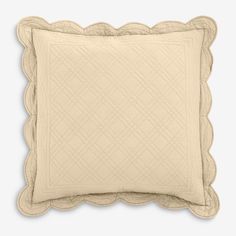 a cream colored pillow with scalloped edges on a white background, in the shape of a square