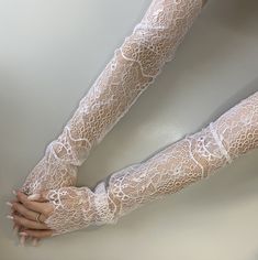 a woman's arm with white lace on it and her hands in the air