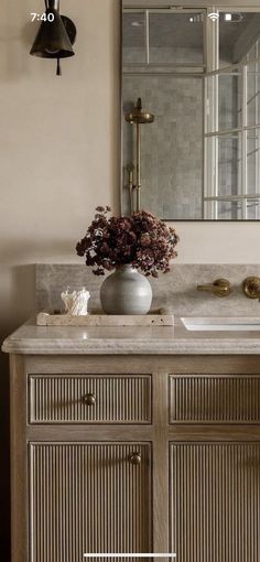 a bathroom with a sink, mirror and flowers on the counter top in front of it