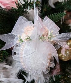 an ornament hanging from a christmas tree decorated with pink and white flowers on it