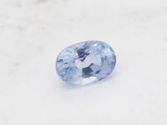 a light blue oval shaped gemstone on a white surface with the top half cut off