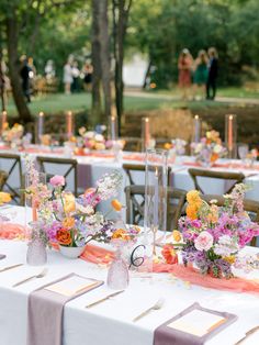 the tables are set up with flowers and candles for an outdoor wedding reception in the woods