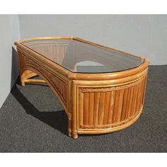 a coffee table made out of wicker with glass top on carpeted flooring