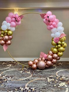 a balloon arch with pink, gold and white balloons in the shape of a wreath