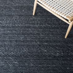 a black rug with white lines on it and a wooden chair in the corner next to it