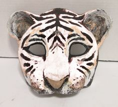 a white tiger mask with black stripes on it's face is shown in front of a wall