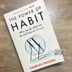 the power of habitt by charles duhigs on a wooden table with a mouse