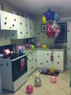 balloons and streamers fill the air in a kitchen decorated with white cabinets, tile flooring