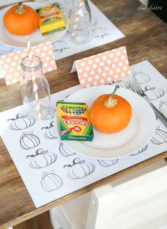 a white plate topped with an orange pumpkin sitting on top of a table next to paper napkins