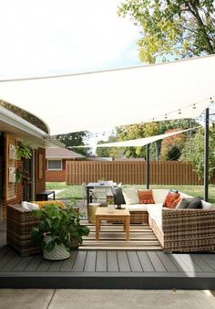 an outdoor living area with couches, tables and chairs under a white awning