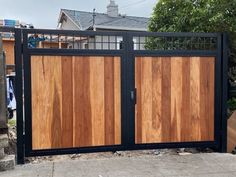 a wooden gate with metal bars on the top and bottom part, in front of a house