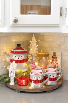 the kitchen counter is decorated for christmas with white and red dishes, mugs and candy canes