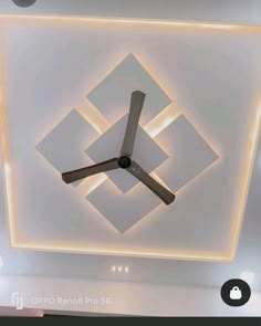 a clock mounted to the ceiling in a room with white walls and lights on it